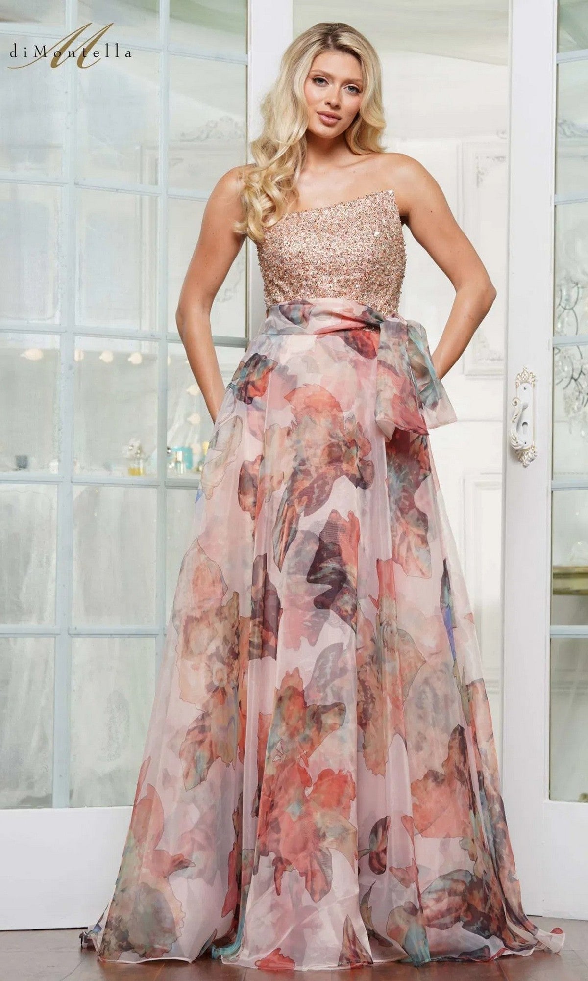 A woman stands indoors wearing the Long Formal Dress: Rina Di Montella RD3213 in mauve, featuring a one-shoulder, beaded bodice and a flowing organza skirt.